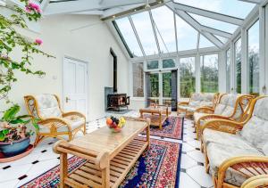 um jardim de Inverno com sofás, uma mesa e cadeiras em Buckland House em Slapton