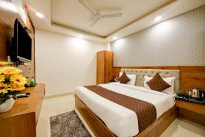 een slaapkamer met een groot bed en een televisie bij Hotel Grand Qubic Near Delhi Airport in New Delhi