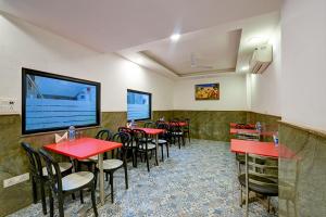 Hotel Grand Qubic Near Delhi Airport في نيودلهي: مطعم بطاولات حمراء وكراسي وتلفزيون بشاشة مسطحة