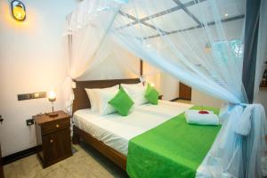um quarto com uma cama de dossel e almofadas verdes em Villa Nine84 Mirissa em Matara