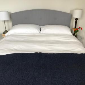 1 cama con sábanas y almohadas blancas y 2 lámparas en Stone street en Faversham
