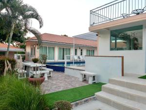 Cette maison dispose d'une terrasse avec une table et des bancs. dans l'établissement Home JANO, à Cha Am