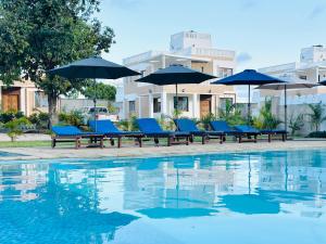 a group of blue chairs and umbrellas next to a pool at 3 Bedroom Luxury Villa-Sita in Diani in Kinondo