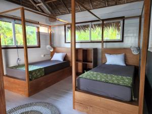 2 camas en una habitación con ventanas en Leleu Mentawai Accommodation, en Tua Pejat
