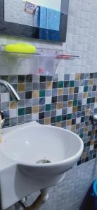 ein weißes Waschbecken im Bad mit einer gefliesten Wand in der Unterkunft Shriya Homestay in Kurseong