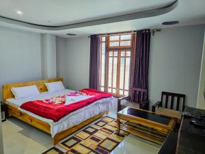 a bedroom with a bed and a table and a window at Hotel Kimnas in Tawang
