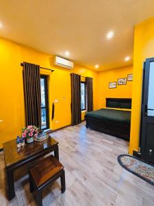 ein Wohnzimmer mit gelben Wänden, einem Bett und einem Tisch in der Unterkunft Old Quarter Bat Su Ha Noi in Hanoi
