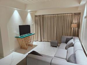 ein Wohnzimmer mit einem Sofa und einem TV in der Unterkunft Sovereign Sanctuary in Guwahati