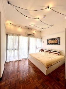 1 dormitorio con 1 cama con cortinas blancas y suelo de madera en The Brooklyn en Bentong