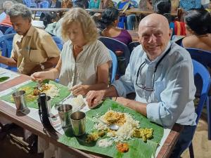 an older man sitting at a table with a plate of food at Lakeview homestay in Kokkānisseri