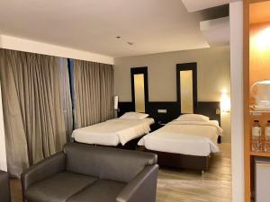 a hotel room with two beds and a couch at Gold Orchid Bangkok Hotel in Bangkok