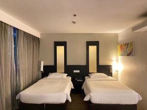 a hotel room with two beds and a window at Gold Orchid Bangkok Hotel in Bangkok