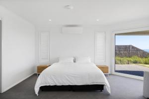 una camera con un letto bianco e una grande finestra di Seaside Sanctuary - Pool and Beachfront a Ventnor