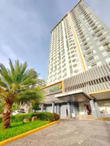 a large building with a palm tree in front of it at Topaz 1 Bedroom Suite Orochi Staycation PH at Centrio Towers in Cagayan de Oro