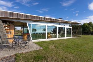 a house with large glass doors and a patio at Kina Retreat - Luxury Nelson Getaway in Tasman
