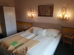 a bed in a bedroom with two lights on the wall at Hotel Goldflair am Rathaus in Korbach