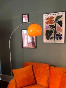 een oranje lamp in een woonkamer met een bank bij Elegant, quirky home in up-and-coming Wolverton in Wolverton