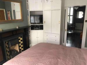 sypialnia z łóżkiem, kominkiem i telewizorem w obiekcie Elegant, quirky home in up-and-coming Wolverton w mieście Wolverton