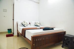 1 dormitorio con 1 cama con sábanas y almohadas blancas en SIYA RESIDENCY, en Ernakulam