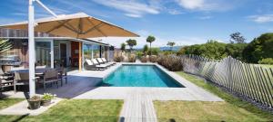 a backyard with a swimming pool and an umbrella at Kina Retreat - Luxury Nelson Getaway in Tasman