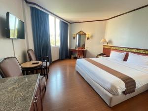 Habitación de hotel con cama y mesa en Wangcome Hotel, en Chiang Rai