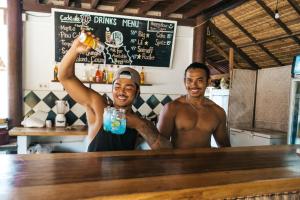 two men standing at a bar holding a drink at Mango Tree House in Gili Trawangan