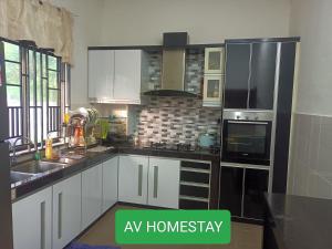 a kitchen with white cabinets and black appliances at AV HOMESTAY in Kuantan