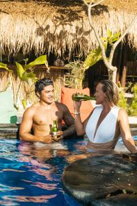 a man and woman drinking beer in a swimming pool at Mango Tree House in Gili Trawangan