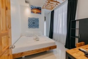 Schlafzimmer mit einem Bett mit weißer Bettwäsche und einem Fenster in der Unterkunft The Marc Vannelli Oslob in Oslob
