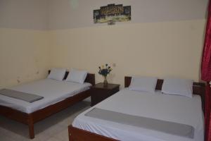 a bedroom with two beds and a vase of flowers at OYO 93736 Homestay Joglo Dephis Syariah in Magelang
