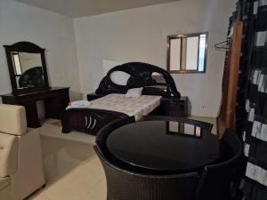 a room with a bed and a table and a mirror at Monteiro Paradise Guest House in São Tomé