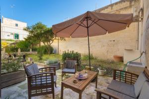 un patio con mesa, sillas y sombrilla en Dongiovanni Suite, en Lecce
