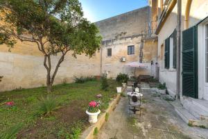 a garden with benches and a tree and a building at Dongiovanni Suite in Lecce