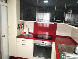 a red and white kitchen with a stove and a sink at Casa Cris in Córdoba