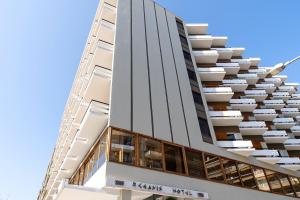 a tall white building with balconies on it at Oceanis Hotel in Kavala