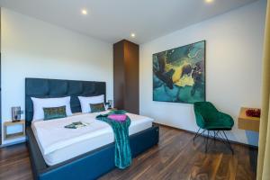 a bedroom with a bed and a green chair at Villa Abba Rakalj - Meerblick, Luxus und Komfort an der Südostküste Istriens in Rakalj +74 photos