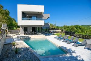 a house with a swimming pool and lounge chairs at Villa Abba Rakalj - Meerblick, Luxus und Komfort an der Südostküste Istriens in Rakalj