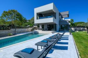 a house with a swimming pool and lounge chairs at Villa Abba Rakalj - Meerblick, Luxus und Komfort an der Südostküste Istriens in Rakalj