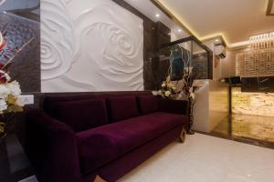 OYO Flagship Hotel Park Palace في مومباي: غرفة معيشة مع أريكة أرجوانية أمام الجدار