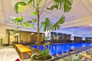 a pool with a bench and a palm tree in a building at Metropolis Dream in Auckland