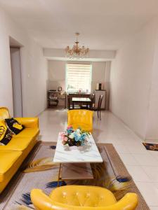a living room with a yellow couch and a table at The Trails Kampar in Kampong Malim Nawar