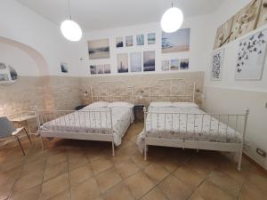 twee bedden in een kamer met foto's aan de muur bij Trio D'Archi - La Maison de Cocò in Caltagirone