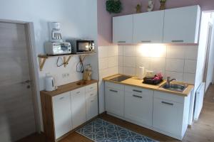 Elle comprend une petite cuisine avec des placards blancs et un évier. dans l'établissement Apartmenthaus Kestel, à Kirchbach