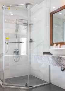een glazen douche in een badkamer met een wastafel bij Cat Ba Paradise Hotel- Pool & Sky Bar in Cat Ba