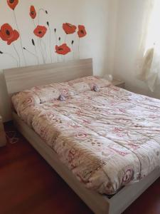 a bed in a bedroom with red flowers on the wall at La Casa di Boh, vicino ospedale San Paolo, Iulm, Forum Assago in Milan
