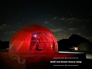una cúpula roja iluminada por la noche en Wadi rum anwar luxury camp, en Wadi Rum