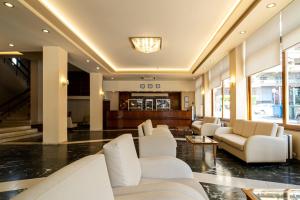 a lobby of a hotel with white chairs and tables at Oceanis Hotel in Kavála