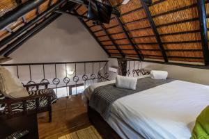 um quarto com uma cama e uma cadeira num quarto em Ndumu River Lodge em Jozini