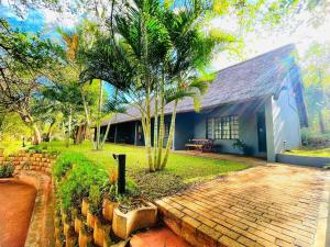 a house with a palm tree in front of it at Ndumu River Lodge in Jozini