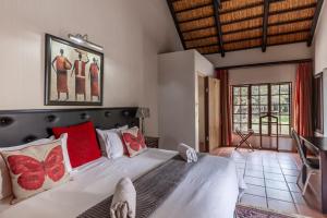 1 dormitorio con 1 cama blanca grande con almohadas rojas en Ndumu River Lodge en Jozini